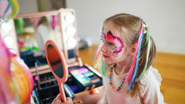 Artist painting little preschooler girl like unicorn on a birthday party